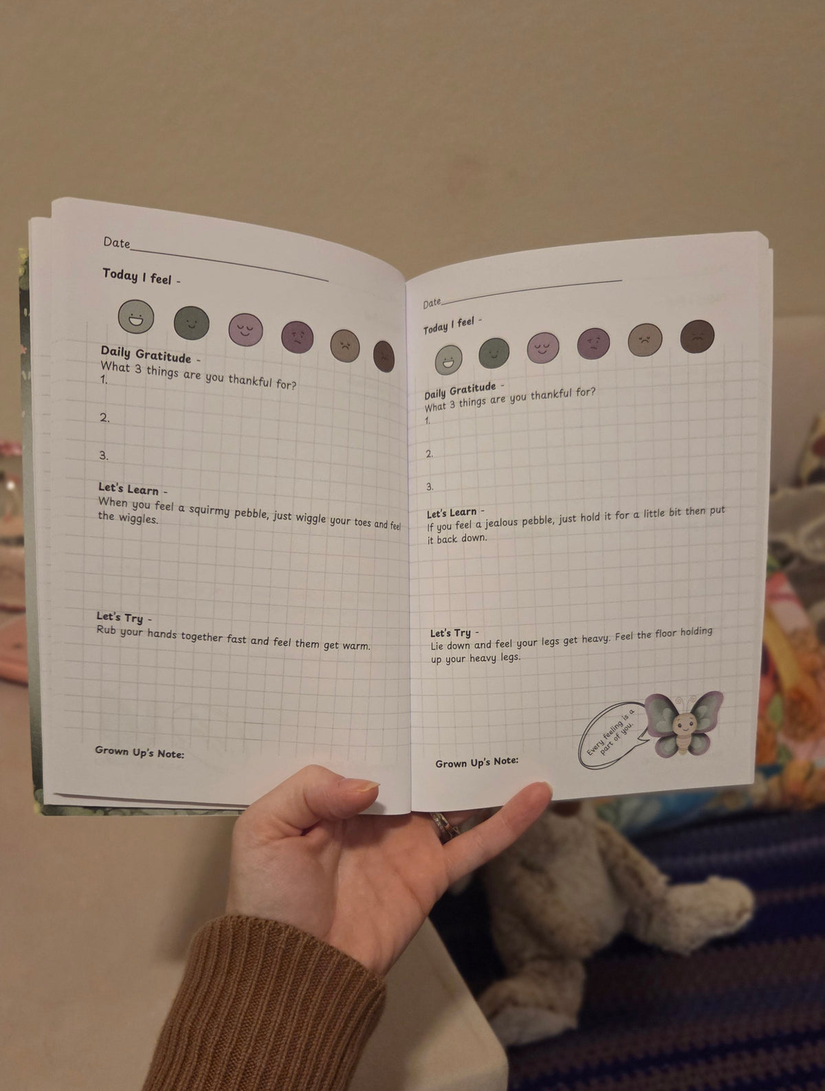 Close-up of The Pebble Path CBT journal lying open on a cozy rug next to colored pencils.